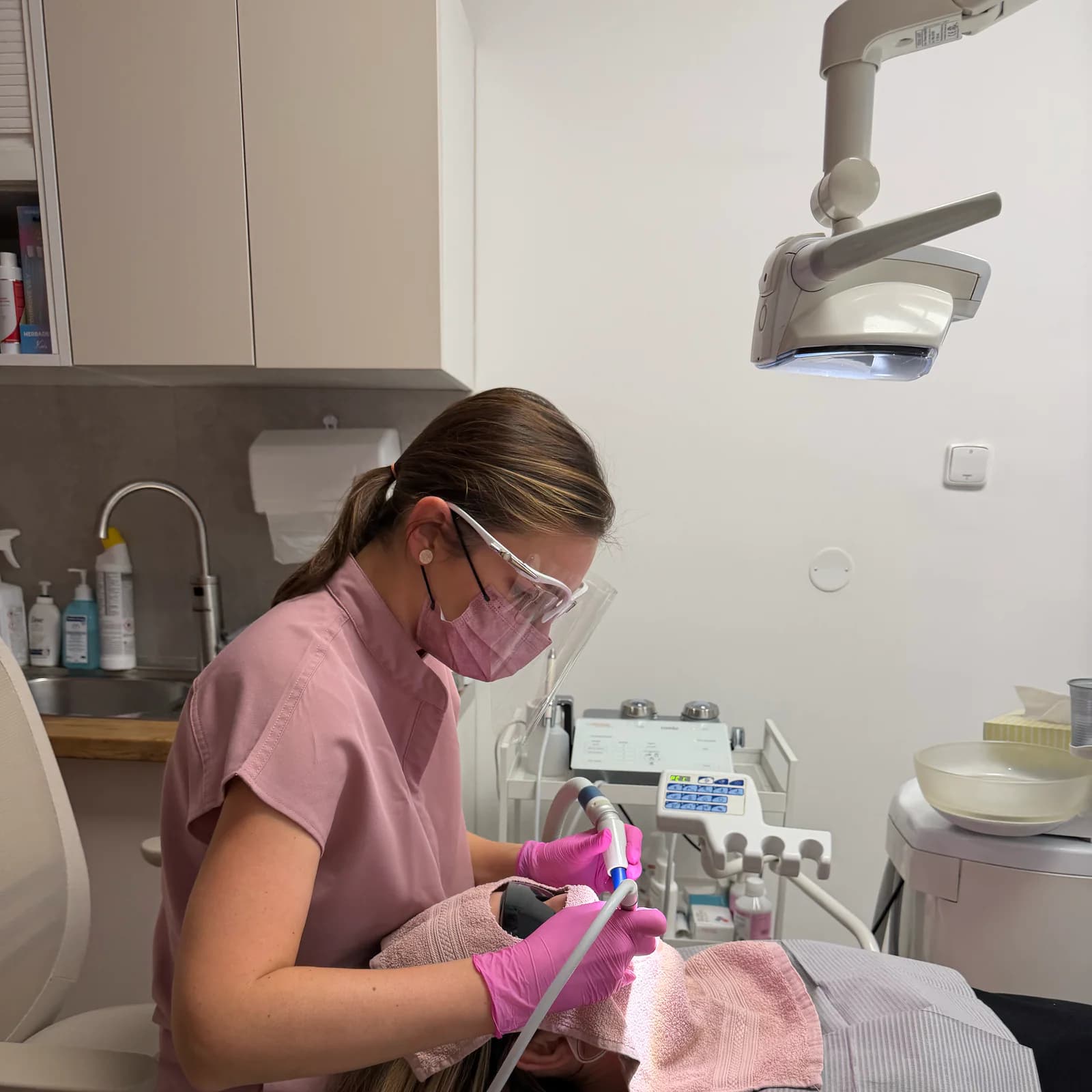 Martina čistí pacientce zuby, v pozadí přístroj na leštění