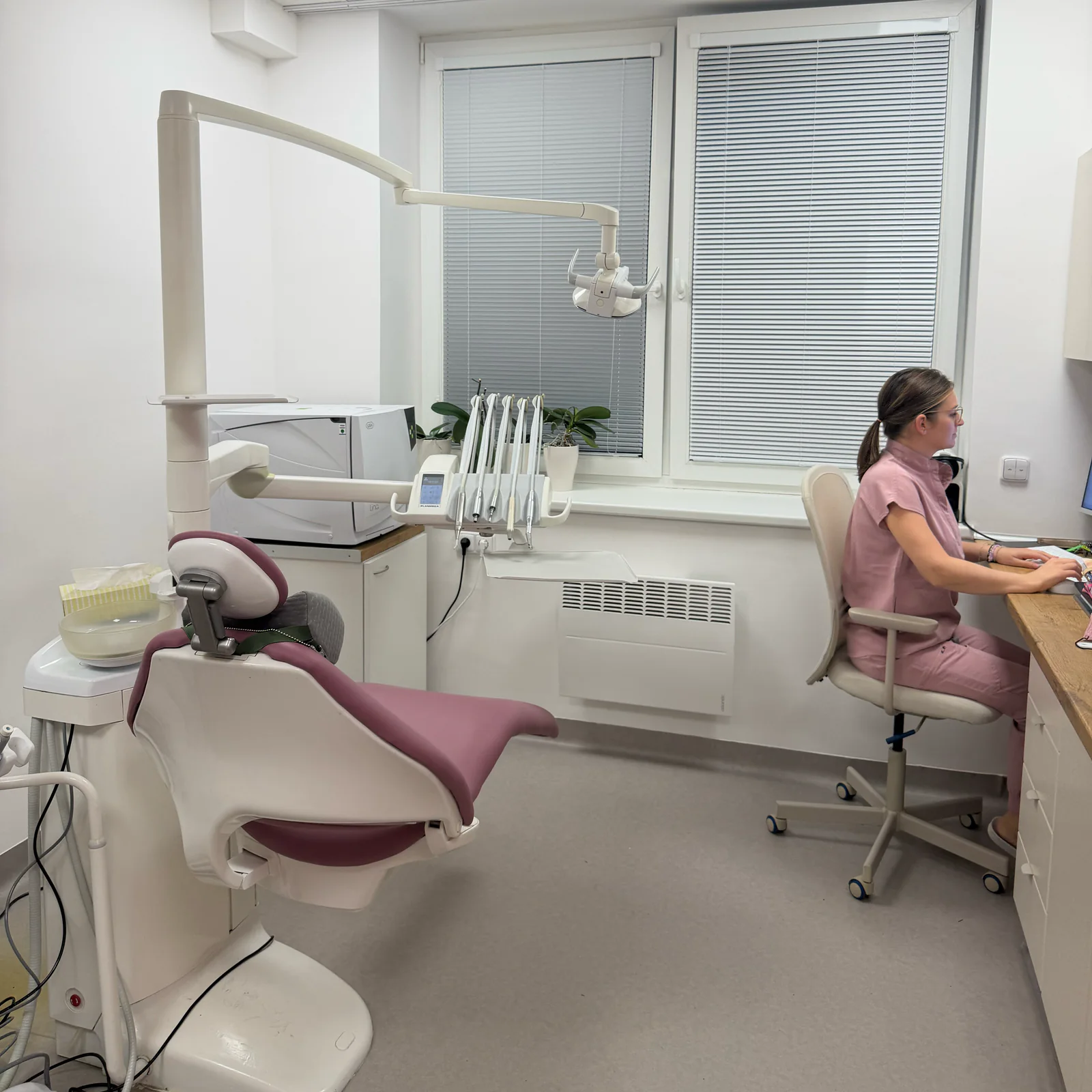 Světlá ordinace s křeslem pro pacienty, Martina u pracovního stolu